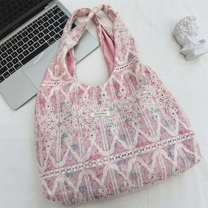 Pink lace tote bag with white hollow patterns shown from top view with office decor