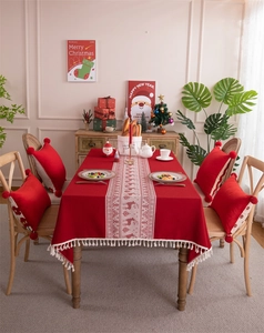 Detail of red Christmas tablecloth with white deer jacquard patterns and elegant fringes