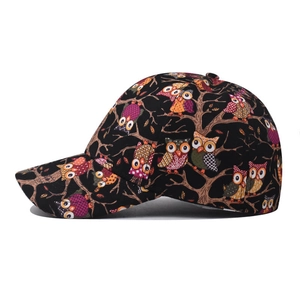 Side view of a black cotton baseball cap with a colorful owl and tree branch print