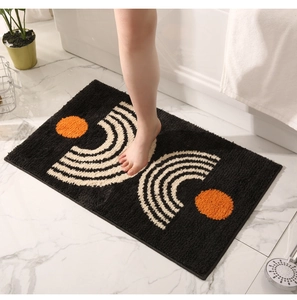 Close-up of minimalist black bathroom mat with orange dots and soft plush texture