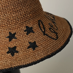 Raffia sun hat with embroidered stars and black lettering in a casual vacation style