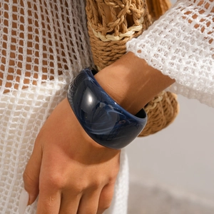 Macro view of wide navy blue resin bangle with white marble patterns on model wrist