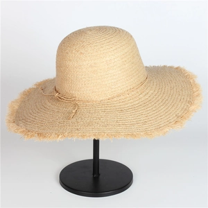 Wide brim raffia straw sun hat with frayed edges and decorative bow for beach vacations