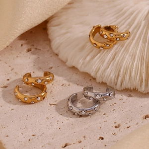 Detailed arrangement of gold and silver C-shaped rhinestone ear cuffs on textured stone