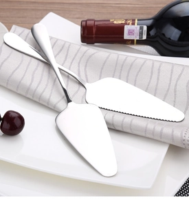 Detailed macro view of two stainless steel cake and pizza servers on a white plate
