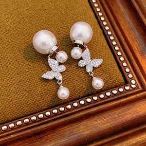Detailed macro view of vintage butterfly pearl earrings set in a dark retro photo frame