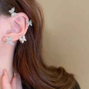 Detailed view of silver butterfly ear cuffs with sparkling crystals on a female ear