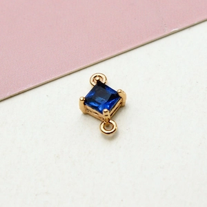 Close-up of a gold-plated geometric rhombus pendant with a deep blue zircon stone