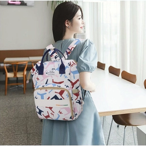 Rear view of model wearing a geometric printed baby diaper backpack with storage pockets