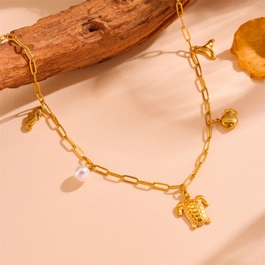 Détails de charms tortue marine et hippocampe dorés sur un collier à maillons trombone