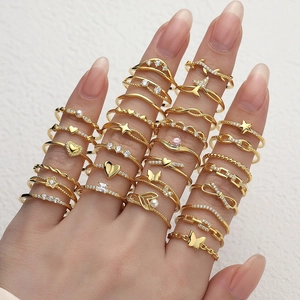 Golden rings set with zircons and faux pearls featuring heart and butterfly designs