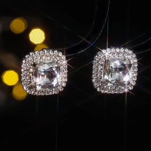 Macro shot of cushion cut square stud earrings with halo setting on black background