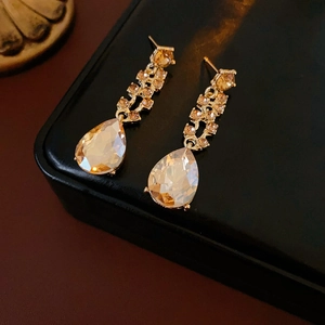 Detail of luxury teardrop champagne crystal earrings with gold plating on black box