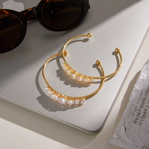 Detailed view of two 18k gold plated open bangles featuring sparkling zircon stones