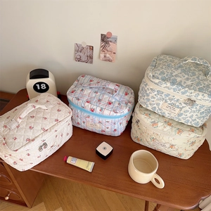 Detailed close-up of quilted floral and plaid makeup bags with double metal zippers
