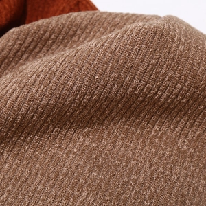 Vue détaillée de la texture du bonnet en maille côtelée marron foncé et rouge rouille