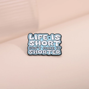 Light blue enamel pin with Life Is Short Don't Make It Shorter quote on pink background