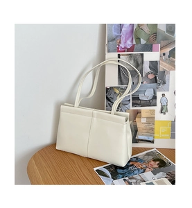 Detail of cream white PU leather tote bag with unique folding stitch on a wooden table
