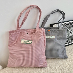 Close-up of checkered canvas tote bag with metal snap button and smiley face embroidery