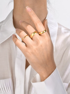 Detailed view of three polished gold stainless steel rings with varying band widths