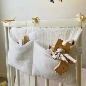 Detail of white double-pocket cotton crib organizer with straps for nursery storage