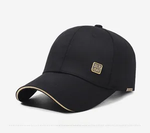 Detail der schwarzen Baseballkappe mit goldenem Metallemblem und seitlichem Webeetikett