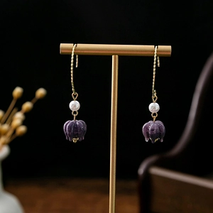 Detail of vintage earrings with gold wire hooks, white pearls and purple flower buds