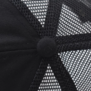 Detailed macro view of black trucker hat top button and breathable mesh panel stitching