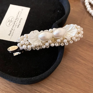 Macro view of handmade French pearl hair clip on black velvet box and wooden background