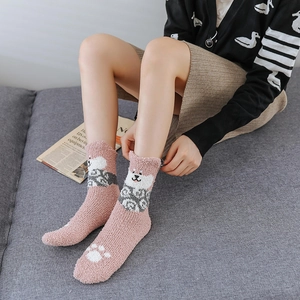 Detailed texture of pink coral fleece socks featuring a cute cartoon dog and white paw prints