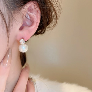 Close-up of elegant pearl and zircon stud earrings featuring a refined golden finish