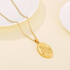 Macro shot of oval gold necklace pendant featuring the Virgin Mary and Child relief