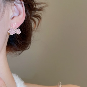 Gros plan de boucles d'oreilles cerisier en résine rose portées sur un modèle