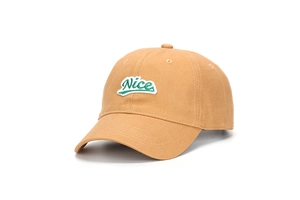 Détail de la broderie Nice verte sur une casquette de baseball en coton moutarde