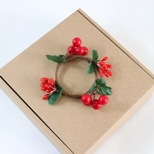 Detail view of red Christmas berry napkin ring with green leaves on a paper box