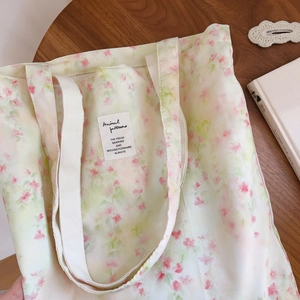 Vue à plat d'un sac cabas en coton à fleurs roses avec anses tissées blanches