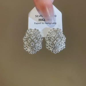 Détail de boucles d'oreilles en dentelle d'argent avec zircons sur fond marron