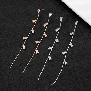 Macro view of long tassel earrings with baguette-cut zircons in silver and rose gold