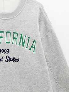 Gros plan du sweat gris avec broderie California 1993 et texture de maille détaillée