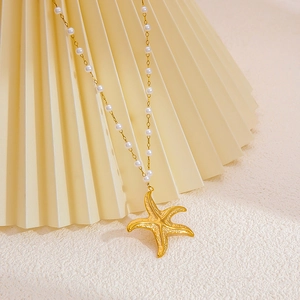 Starfish pendant necklace with gold plated texture and white pearls on an elegant fan