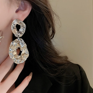 Macro detail of silver geometric liquid metal earrings with irregular textured finish