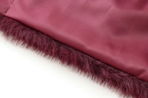 Close-up of burgundy fabric texture and soft faux fur trim on the jacket sleeve