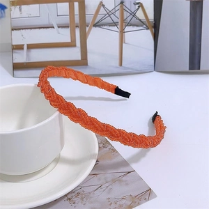 Close-up of orange beaded braided headband next to a white ceramic cup on a desk