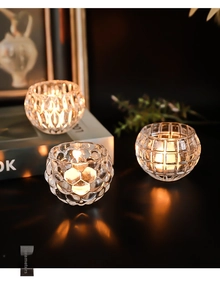 Detailed view of three textured glass pumpkin candle holders with warm tea light glow