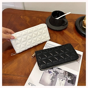 Detailed view of quilted long wallets in black and white leather with zip closure