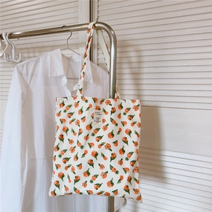 Detail der weißen Canvas-Tasche mit Tulpenprint und zentralem Stoffetikett-Aufnäher