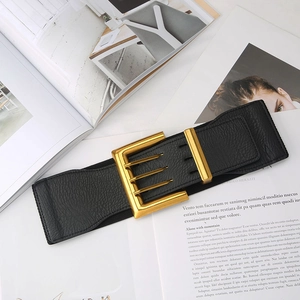 Detail of wide black elastic waist belt with textured finish and golden rectangle buckle