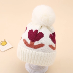 Close-up of baby knit hat with wine red tulip jacquard and large soft pom-pom detail