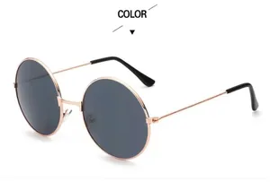 Detail of round sunglasses with a gold metal frame and dark grey tinted lenses