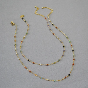 Detail view of colorful natural stone beads on a gold chain with lobster clasp necklace